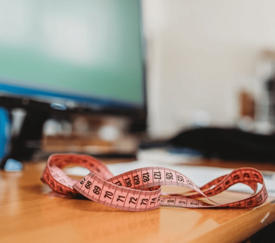 Wizualizacja różowej miary krawieckiej leżącej na biurku