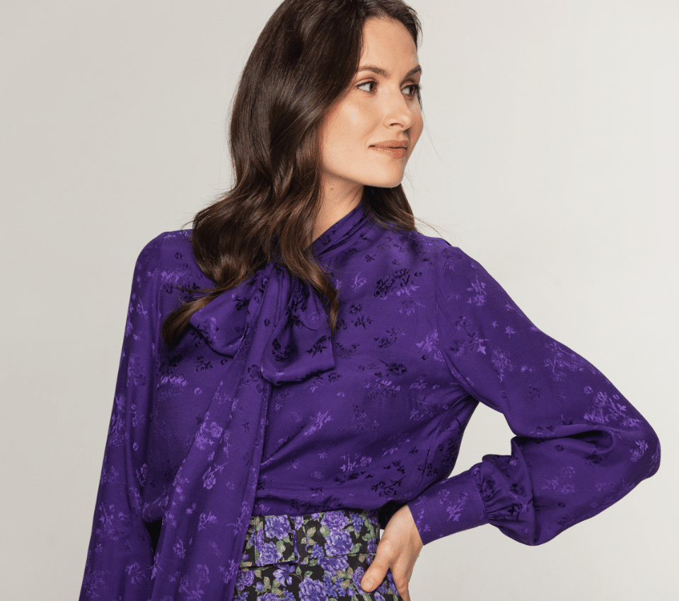 Wizualizacja kobiety w fioletowej bluzce z długim rękawem i wiązanym kołnierzem w jednolity wzór