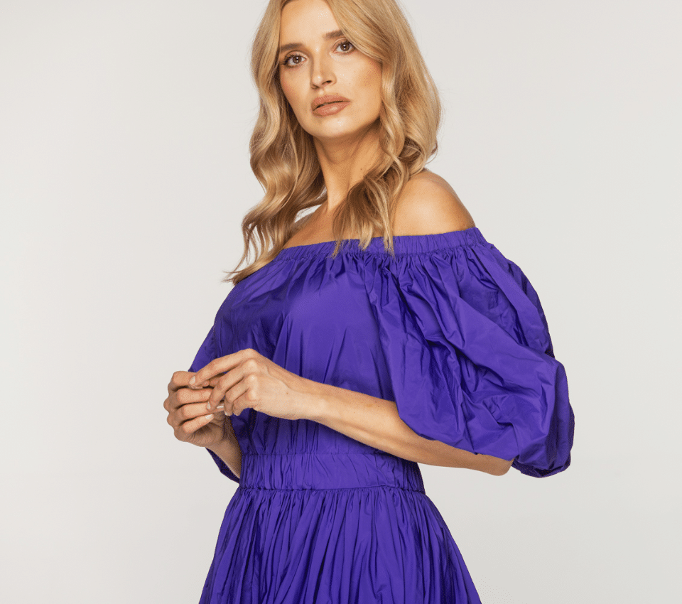Wizualizacja kobiety w fioletowej sukience z dekoltem carmen, z bufiastymi rękawami i elastycznym marszczeniem w pasie