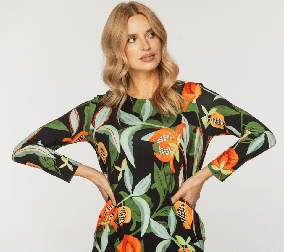 Wizualizacja kobiety w czarnej sukience z długim rękawem, w wyrazisty pomarańczowo-zielony wzór liści