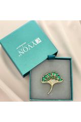 A gold brooch in the shape of a ginkgo leaf with green cubic zirconia stones