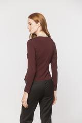 A burgundy knitted blouse with a wrap neckline and ruffles down the side
