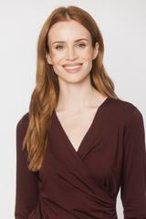A burgundy knitted blouse with a wrap neckline and ruffles down the side